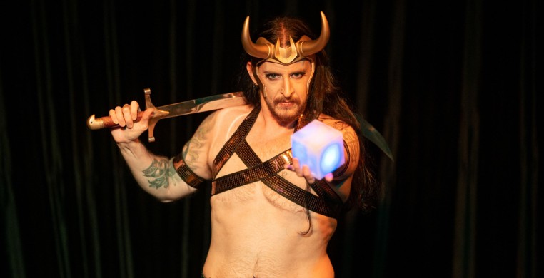 Trans masculine bellydancer in Loki cosplay with a sword