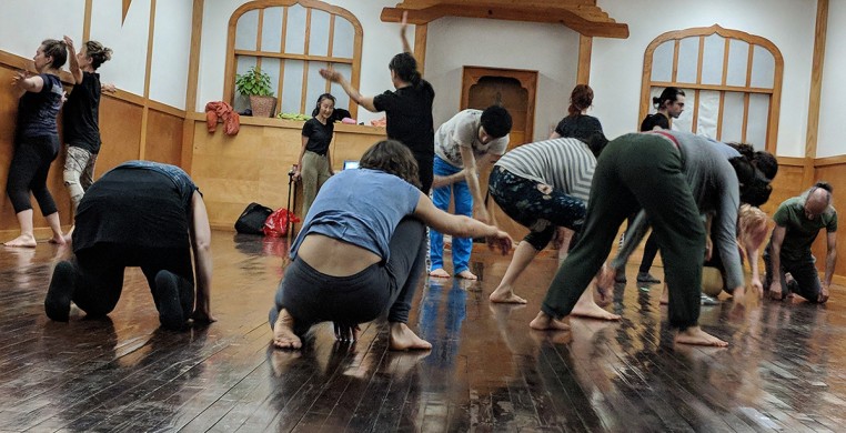 A group of bodies moving along the walls and dark wood floor of a classic Japanese Dojo in Chicago, IL while Yumiko Yoshioka looks on.